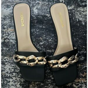 Soda black slip on sandals with large gold chain link accent